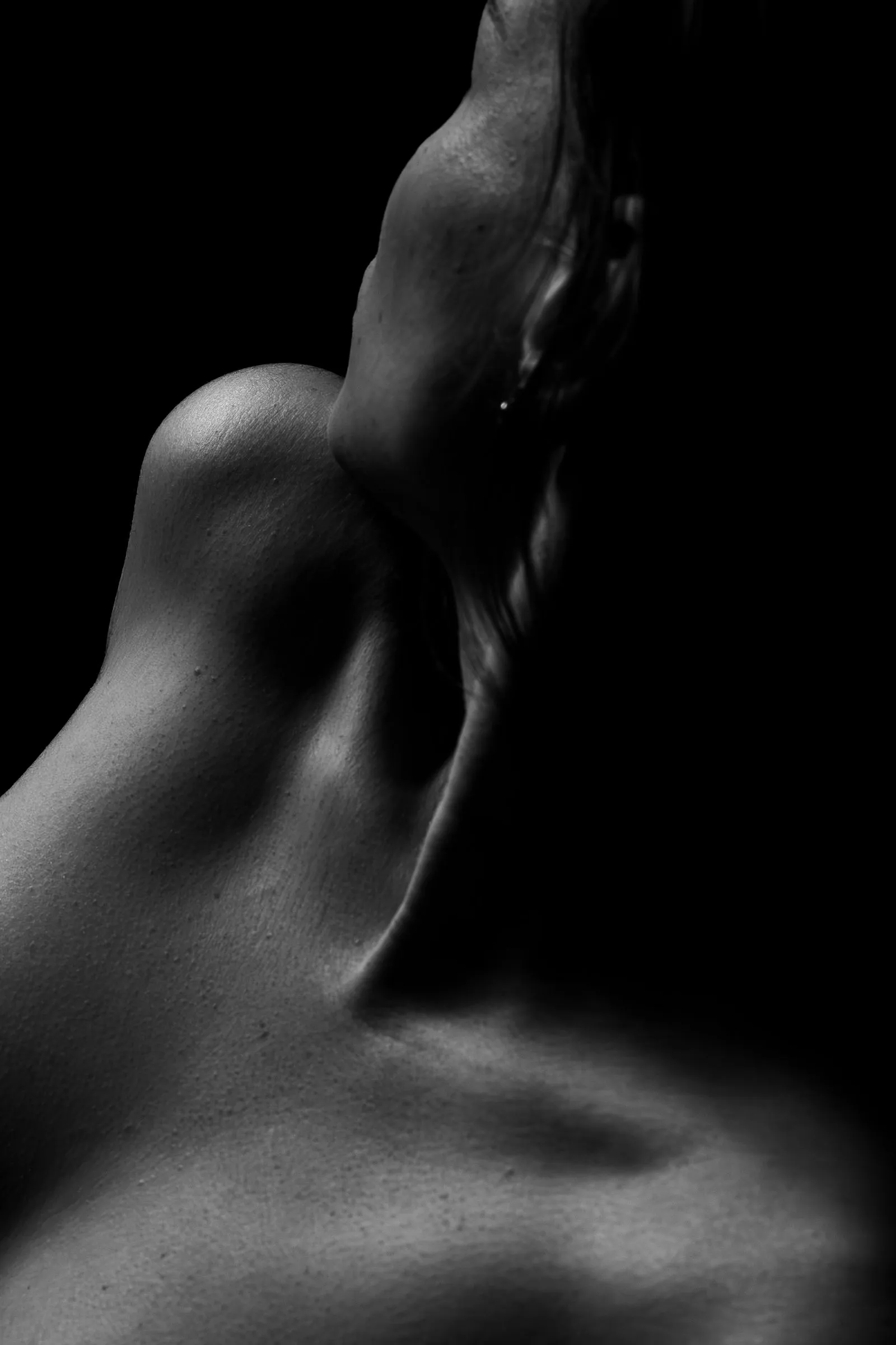Fotografia editorial em preto e branco dos contornos de um ombro; imagem ilustrativa, não representa uma cliente.